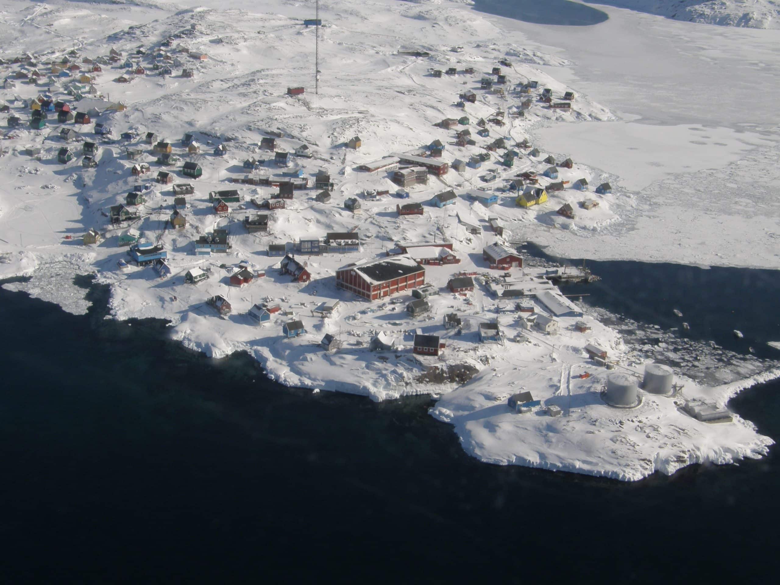 Snowy landscape of coastal village of small hosues in Qeqertalik, Greenland seen from above.