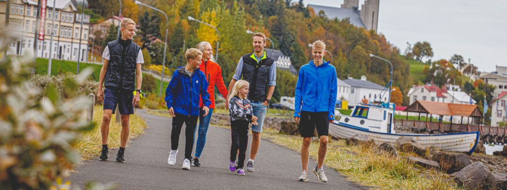 Family with father, mother, 3 sons and a daughter walking by waterfront.